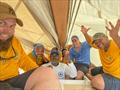Getting out of the rain: Prince William, Duke of Cambridge, under the mainsail with the crew of Bahamian Sloop Susan Chase V after winning the Royal Regatta. L-R: Travis Knowles, Ceri, Security, Claudius, Garret, CJ, William (Duke), Stefan Knowles © Travis Knowles