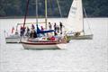 Alicat at anchor while members of Lindsay Tosh's family prepare to scatter his ashes and drop their flowers onto the sea; two of the members' flotilla boats nearby