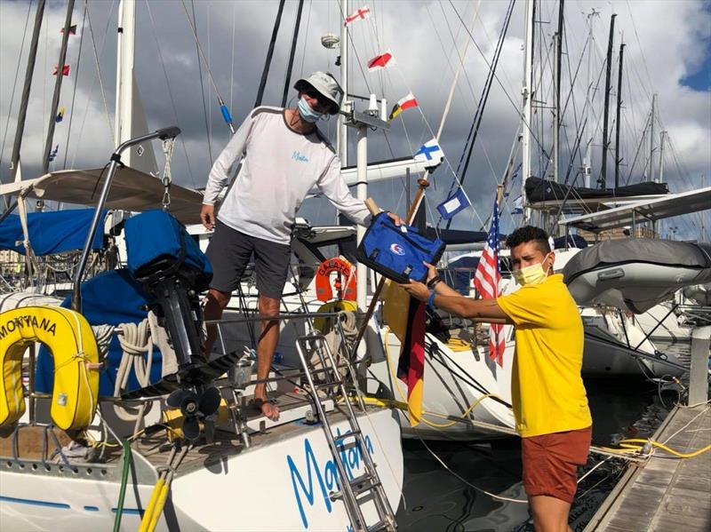Montana receiving a skippers bag for ARC 2020 from ARC yellowshirt Alex photo copyright World Cruising taken at  and featuring the Cruising Yacht class
