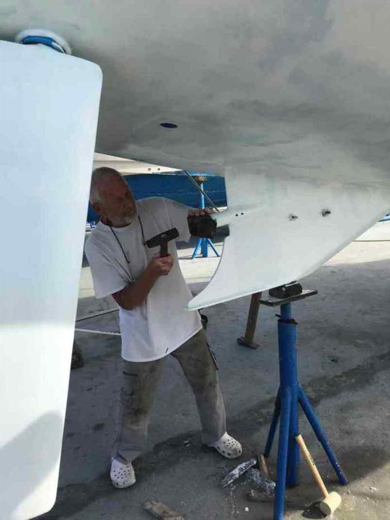 Heinz showing us how to give the Cutlass Bearing some tough love. Note the first coat of white has just gone on (looks a bit patchy covering the blue) photo copyright Red Roo taken at  and featuring the Cruising Yacht class