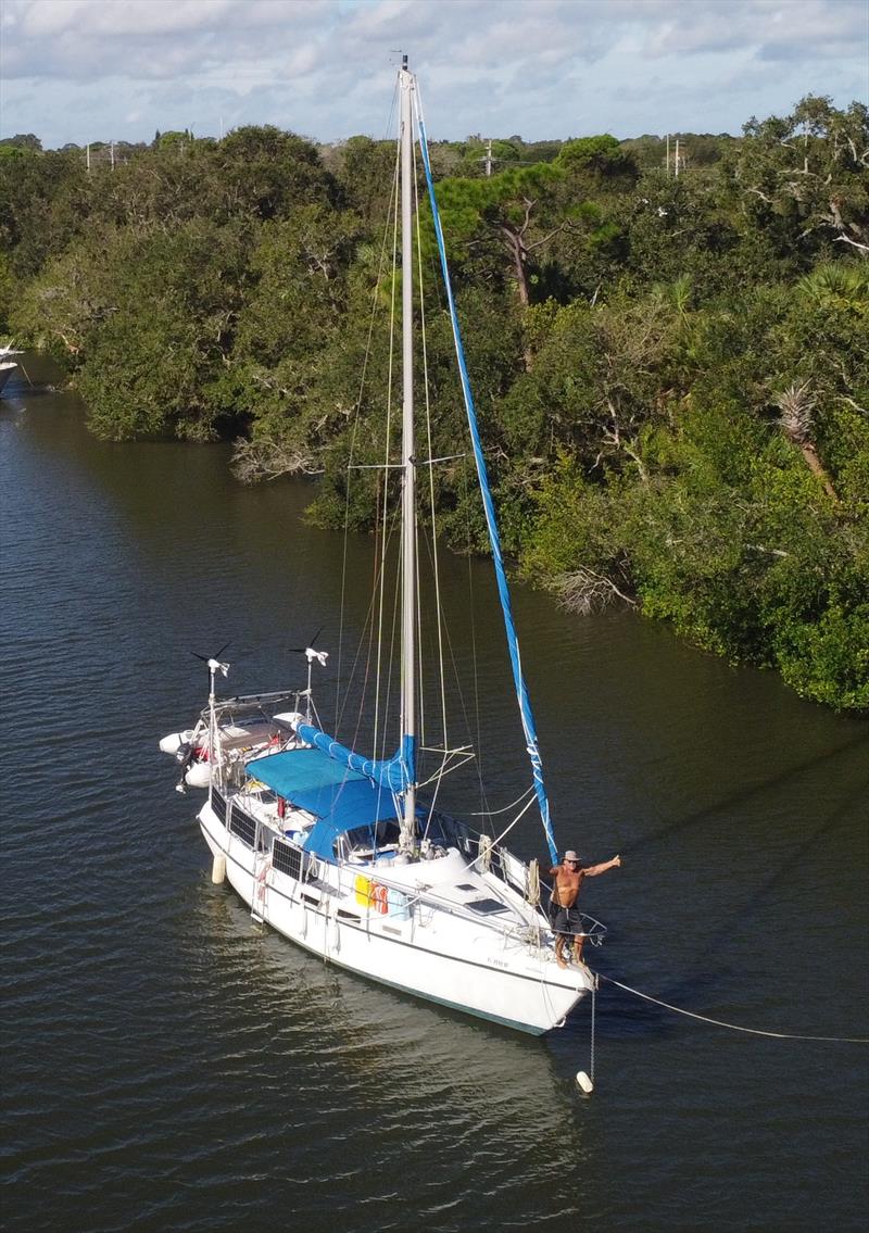 Captain Ken of “Slowpoke” on the morning after Hurricane Nicole, celebrating on the bow of undamaged boat, grateful to the nearby mangrove trees for their shelter during the night before when the storm gusted through at 70 plus mph photo copyright Cade Moore taken at  and featuring the Cruising Yacht class