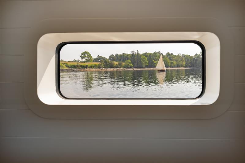 Ouzel, a 95ft superyacht - A passing sailboat is framed by one of Ouzel's rectangular portlights photo copyright Russell Kaye taken at  and featuring the Cruising Yacht class