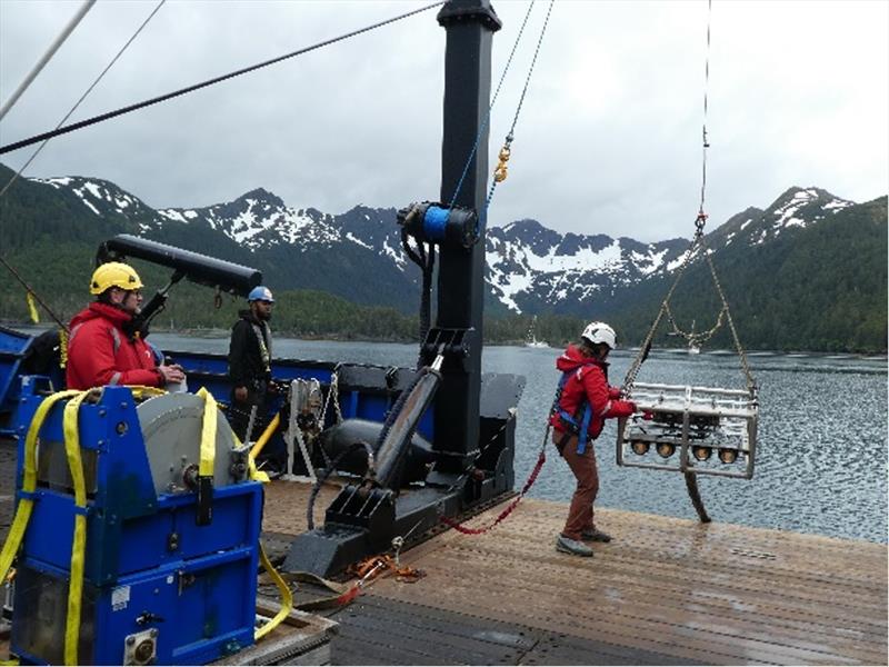 Sean Rooney preparing to deploy stereo drop camera with Brady Glacier of the Fairweather Range. Visibility at this dive site was challenging due to the large amounts of fine sediment discharged by nearby glaciers and by the concentration of phytoplankton. - photo © Pat Malecha, NOAA