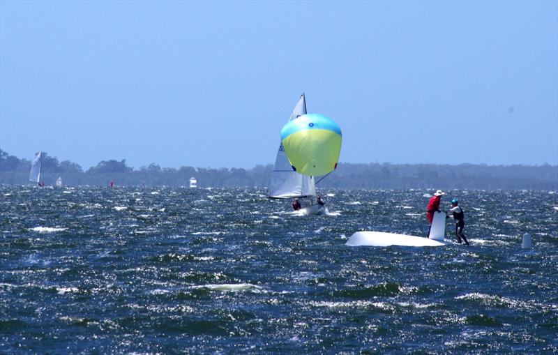 Lupicus NZL112 on the downwind leg approaching an upturned Flying Dutchman, in race five of the FD 2026 Australian championship regatta, held on Lake King at Metung, Australia - photo © Jeanette Severs