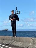 I14 bagpiper while the classics launch for the Classic & Vintage International 14 POW Cup Race 2026 &copy; Neil Munn