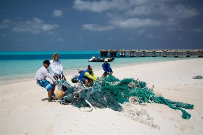 The marine debris team removes a large derelict fishing net from the shallow waters of the Northwestern Hawaiian Islands.  - photo © NOAA Fisheries