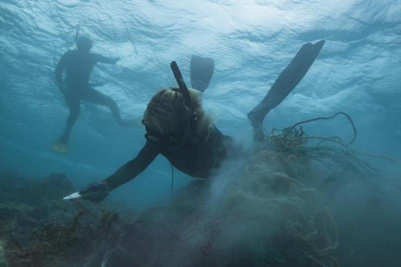 A NOAA marine debris free-diver carefully cuts and removes a large derelict fishing net from the reefs of Manawai (Pearl and Hermes Atoll) photo copyright NOAA Fisheries / Steven Gnam taken at 