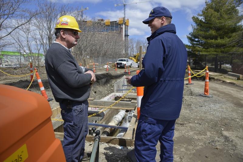 Petty Officer 3rd Class Hayden Hunt discusses freeze pit operations with an Eversource contractor on Friday, April 20, 2018. The unified command is overseeing freeze pit and dive operations this weekend to try and identify the source of the leak. - photo © Petty Officer 3rd Class Nicole J. Groll