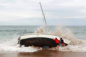 A group of bystanders attempt, unsuccessfully, to manoeuvre the yacht back into the water at Stanwell Park Beach on Sunday. photo copyright Sylvia Liber taken at  and featuring the  class