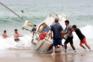 A group of bystanders attempt, unsuccessfully, to manoeuvre the yacht back into the water at Stanwell Park Beach on Sunday. photo copyright Sylvia Liber taken at  and featuring the  class