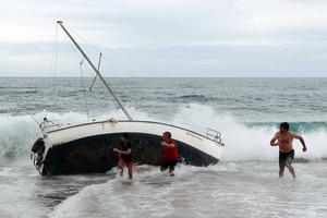 A group of bystanders attempt, unsuccessfully, to manoeuvre the yacht back into the water at Stanwell Park Beach on Sunday. photo copyright Sylvia Liber taken at  and featuring the  class