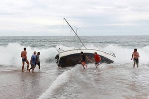 A group of bystanders attempt, unsuccessfully, to manoeuvre the yacht back into the water at Stanwell Park Beach on Sunday. photo copyright Sylvia Liber taken at  and featuring the  class