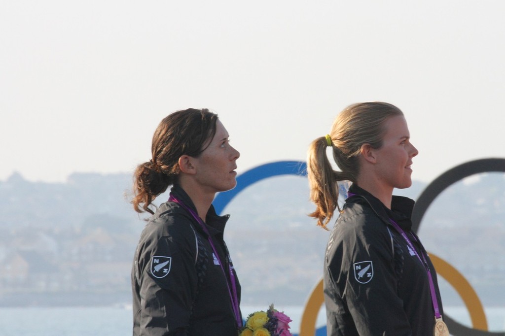  August 10, 2012 - Weymouth, England - Jo Aleh and Olivia Powrie as the NZ Anthem is played at Weymouth © Richard Gladwell www.photosport.co.nz