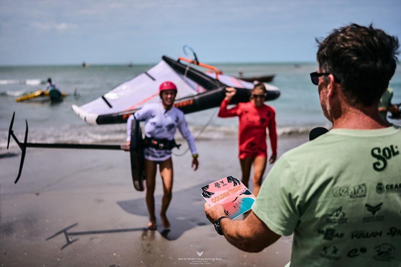 Kylie Belloeuvre steps on to the beach to receive her Golden Ticket - 2024 WingFoil Racing World Cup Brazil photo copyright IWSA media/ Robert Hajduk taken at  and featuring the Wing Foil class